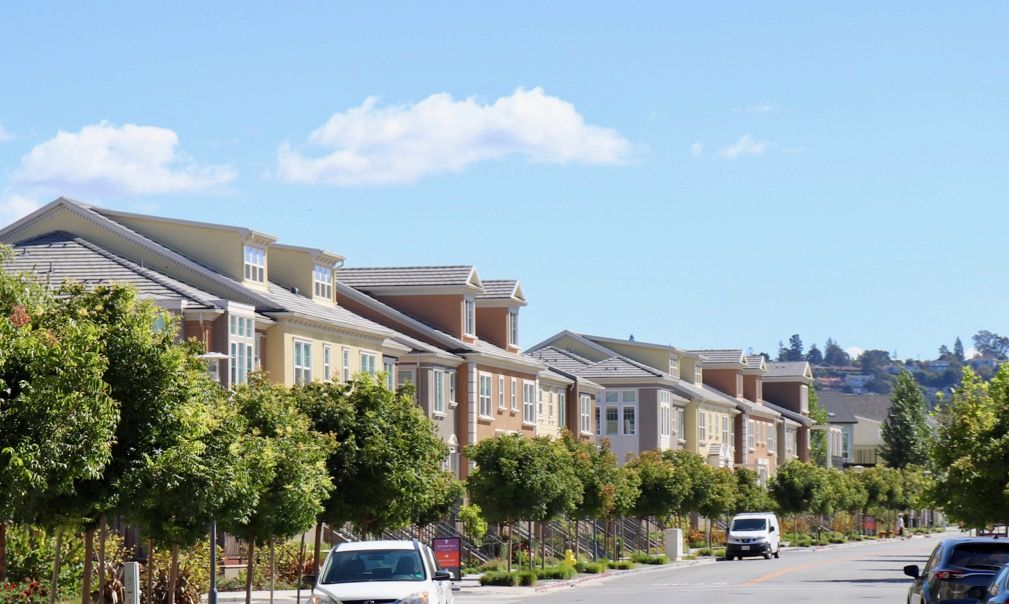 A row of houses with cars parked on the side of the road