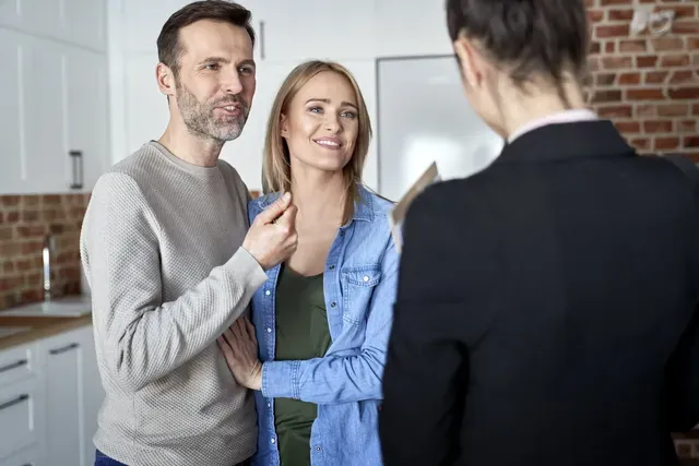 A man and woman are talking to a real estate agent in a kitchen.