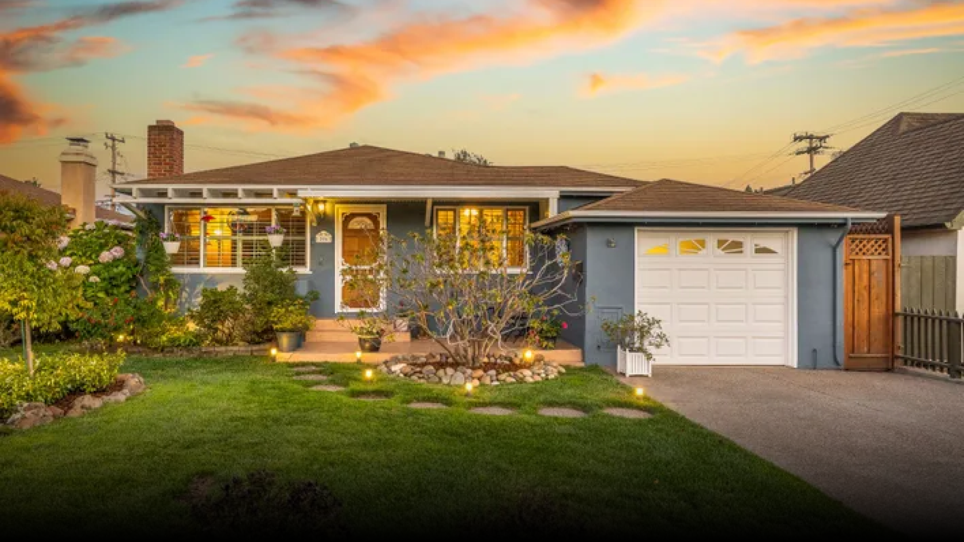 A blue house with a white garage door and a lush green lawn.