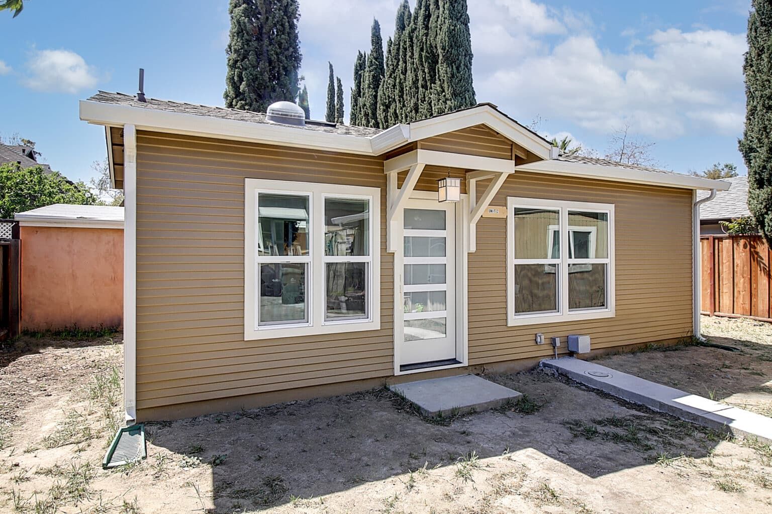 A small house with a porch and a lot of windows.