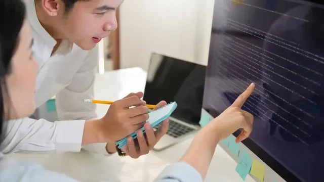 A man and a woman are looking at a computer screen.
