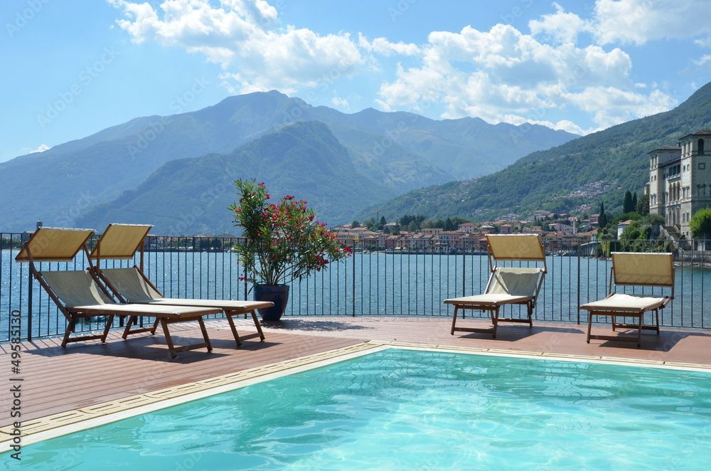 Poolside loungers overlooking a lake and mountains on a sunny day