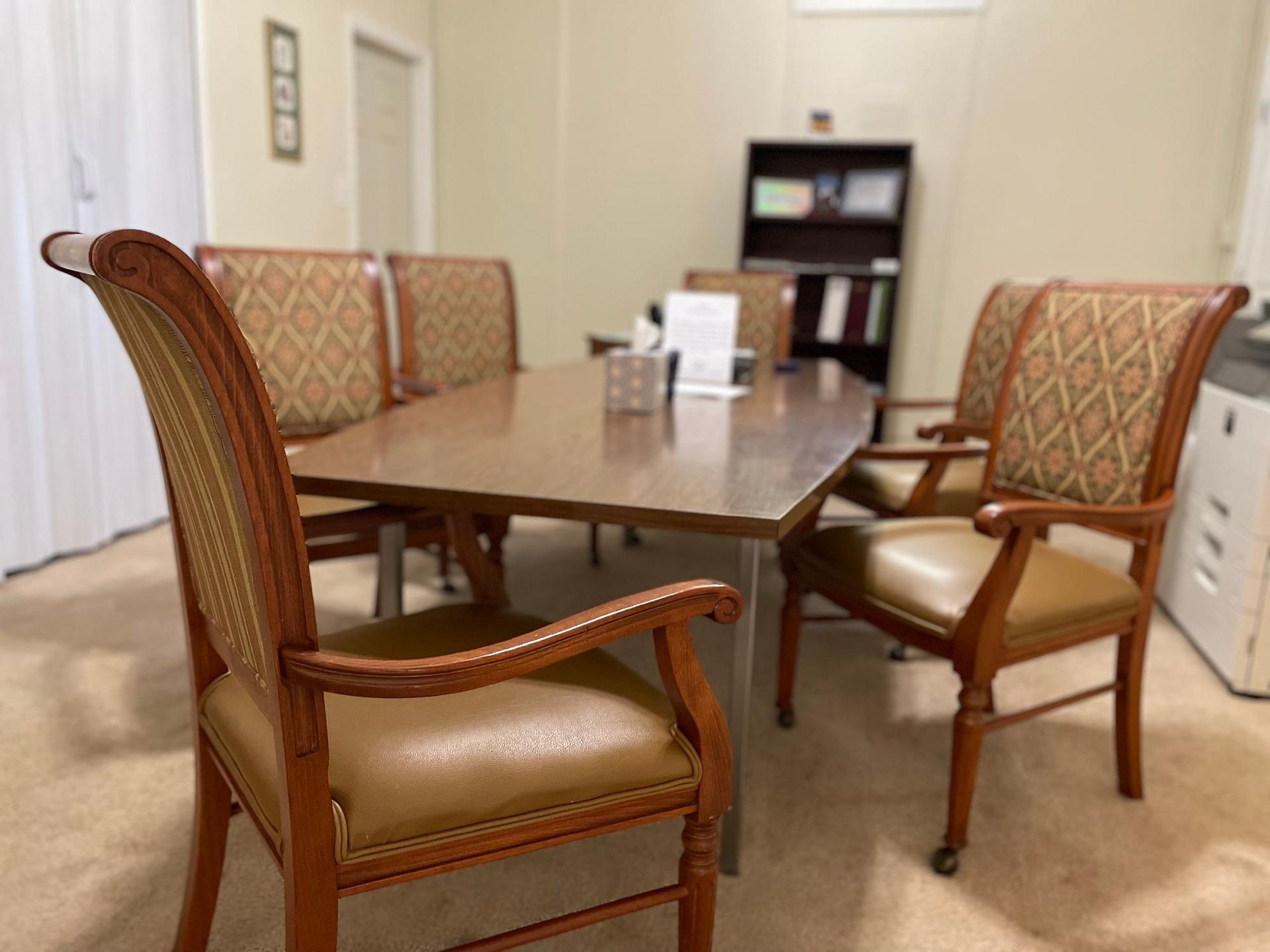Conference room with a wooden table and patterned chairs.