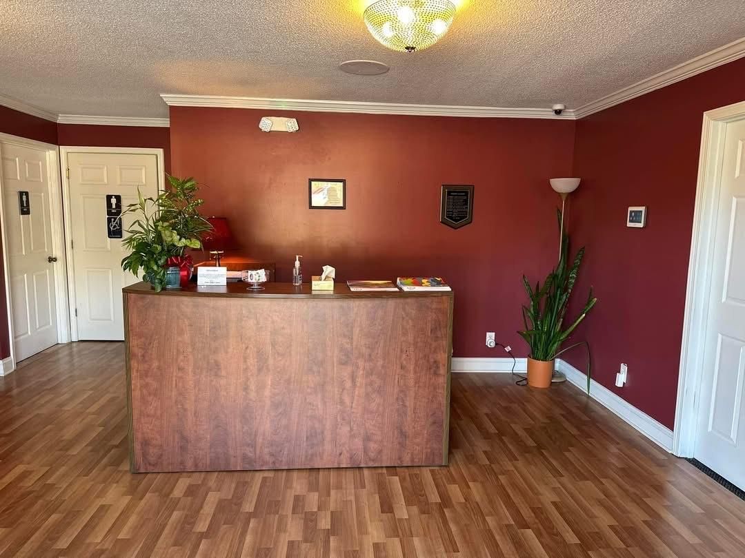 Reception area with wood-look counter, burgundy walls, and two white doors.