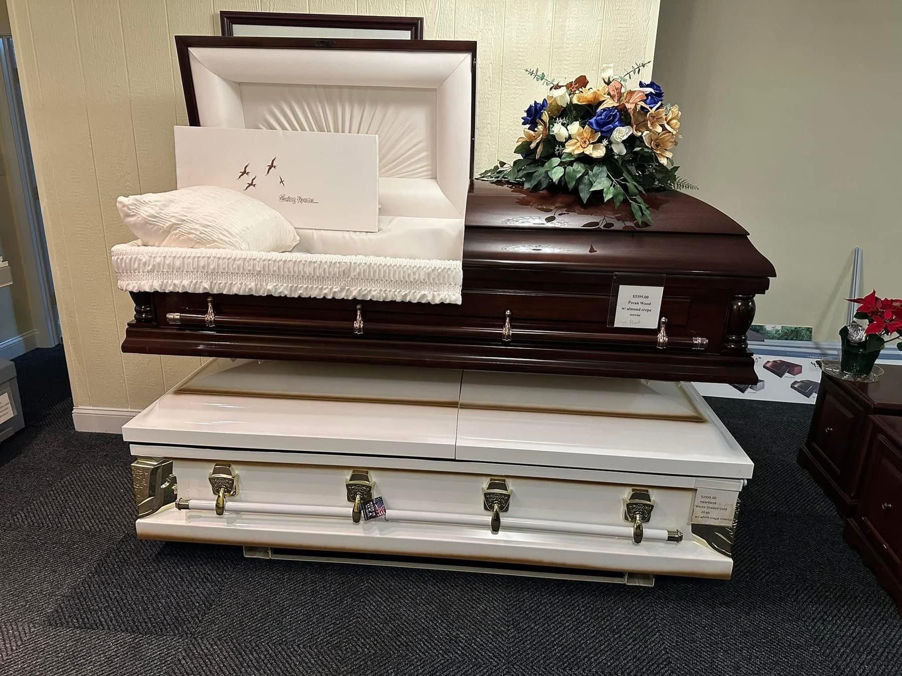 Two open coffins, one on top of the other, displayed in a store. One is brown, the other white.