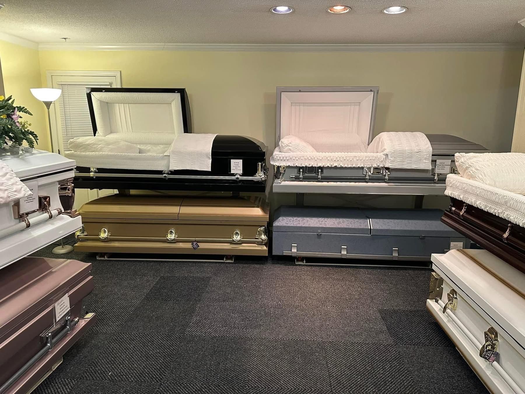 Interior of a funeral home displaying various closed and open caskets in different colors.