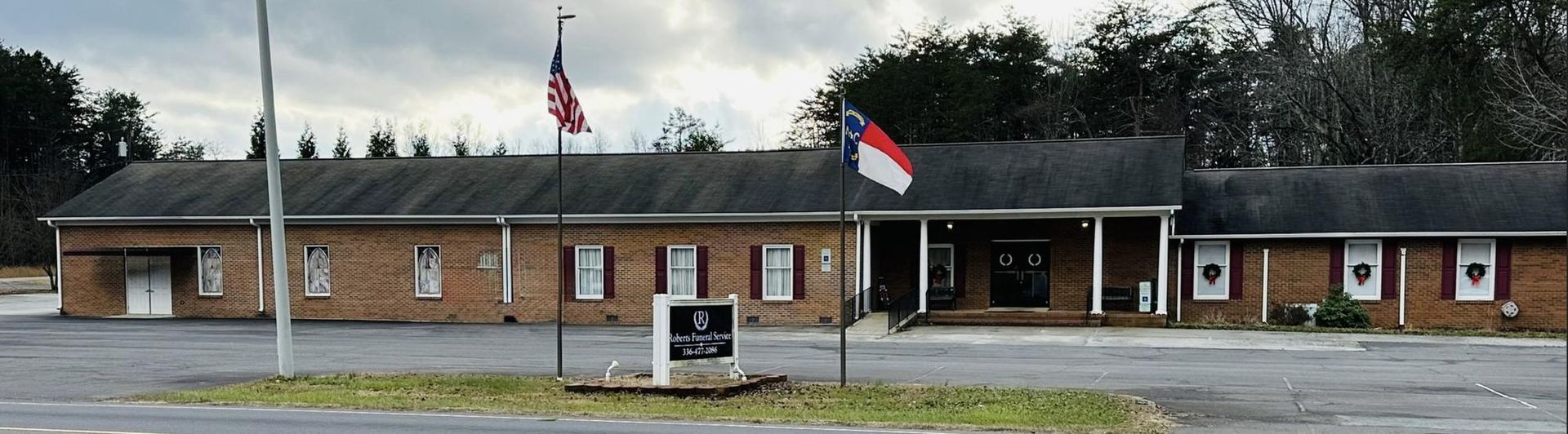 A brick building with an American flag and a North Carolina flag in front.