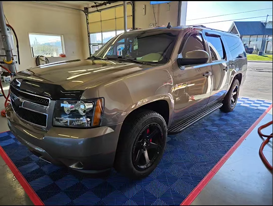 A silver suv is parked on a checkered mat in a garage.