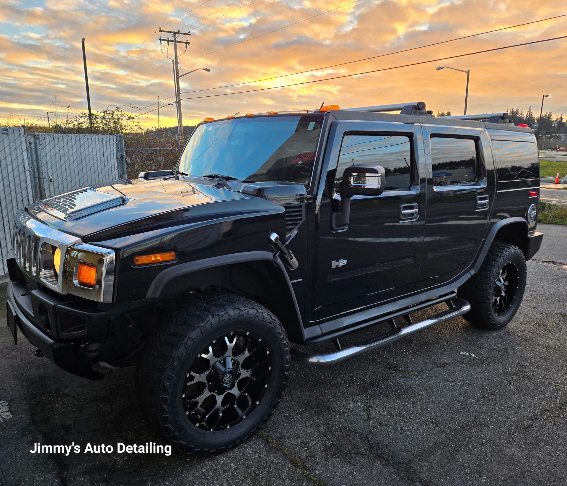 A black hummer is parked in a parking lot at jimmy 's auto detailing.