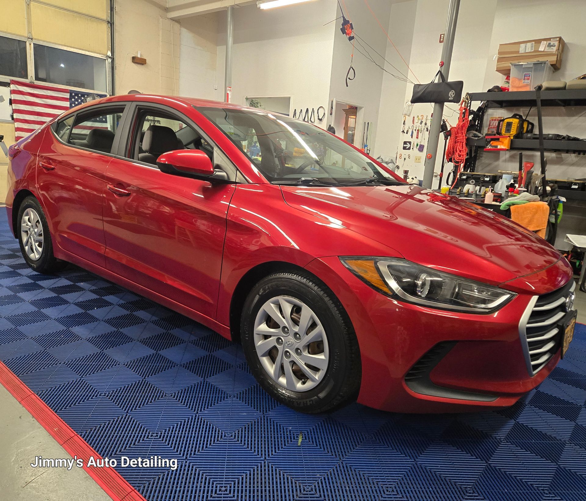 A red hyundai elantra is parked in a garage.