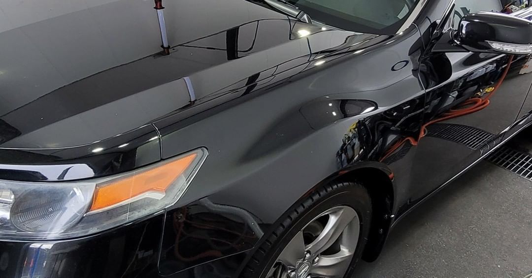 A black car is parked on the side of the road in a garage.