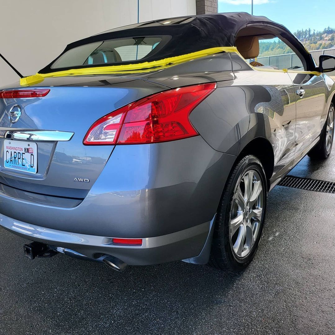 A gray convertible car with a yellow tape on the roof