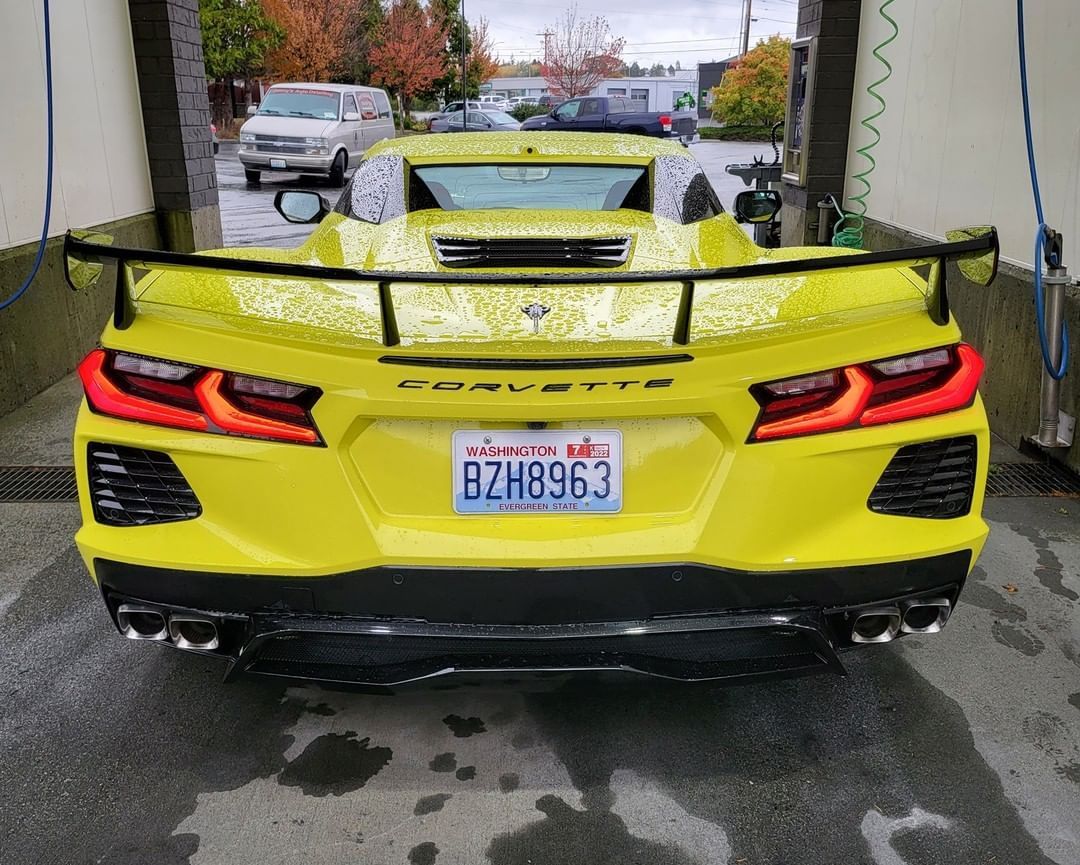 A yellow sports car is parked in a car wash.