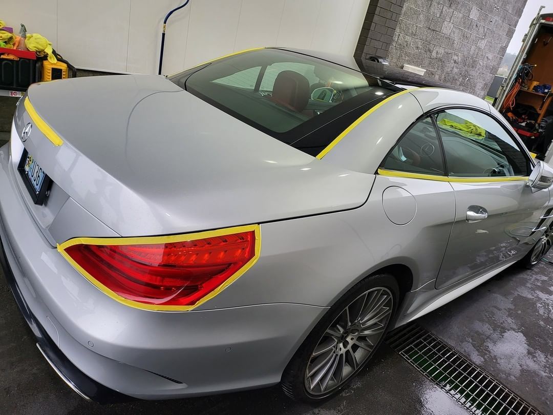 A silver sports car with yellow tape on it is parked in a garage.