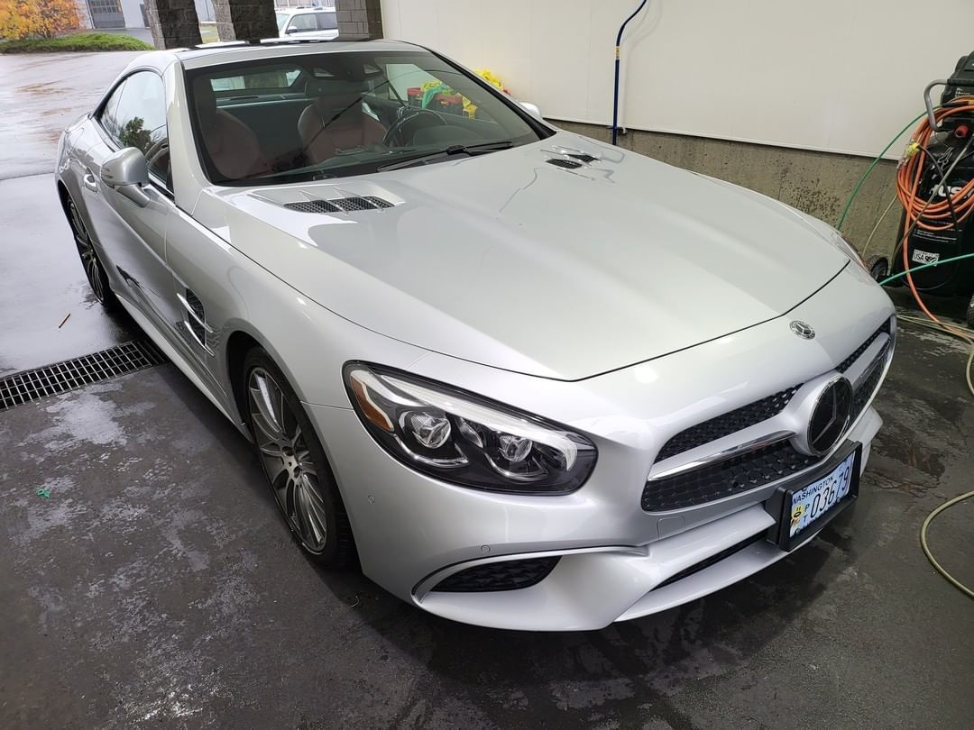 A silver mercedes benz sl500 is parked in a garage.