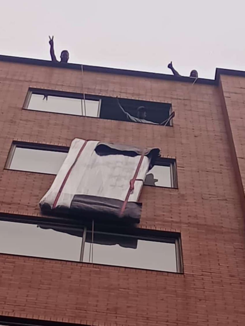 Dos hombres suben un sofá por unas escaleras.