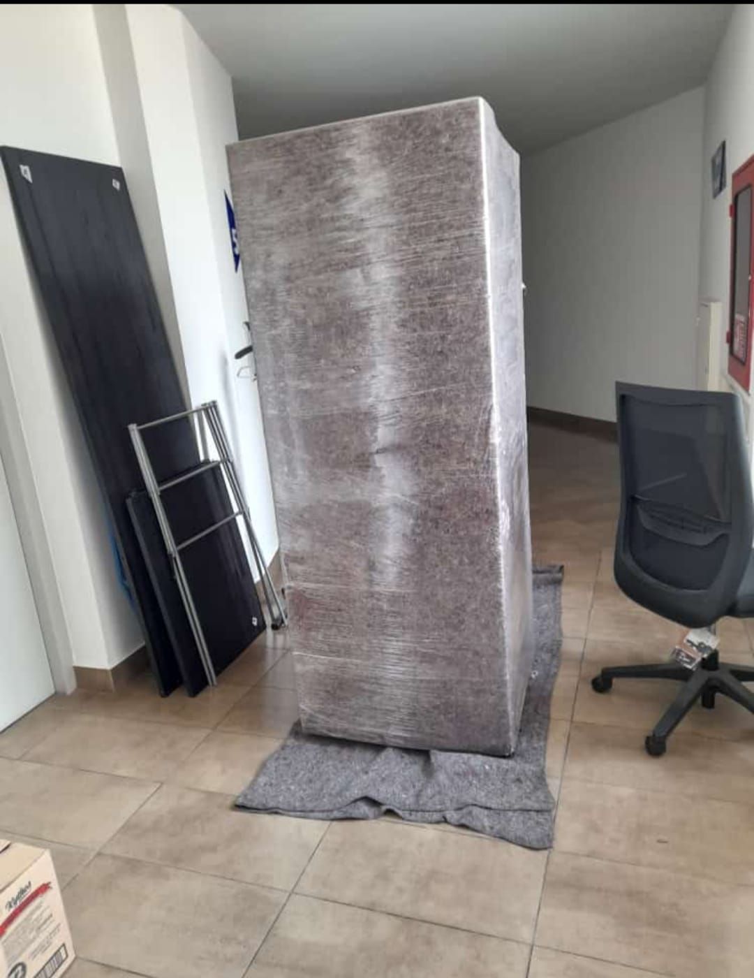 Dos hombres están moviendo un refrigerador en una cocina.