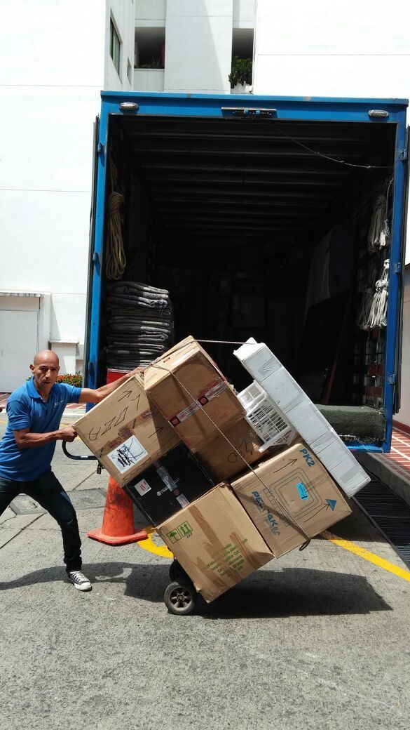 Un hombre carga cajas en un camión de mudanzas mientras una mujer observa.