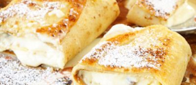 Close-up of fried, pastry-wrapped dessert dusted with powdered sugar.