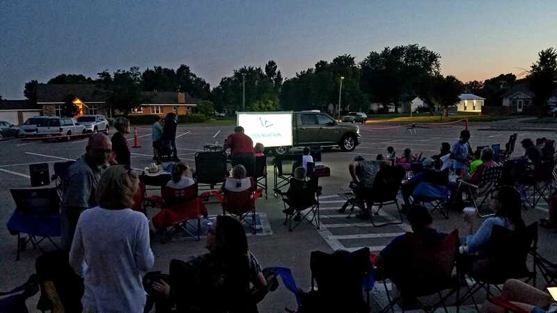 people in lawn chairs observing stars on screen