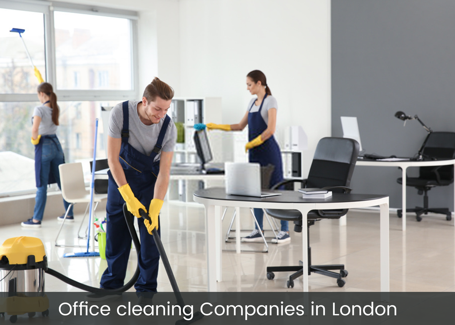 A man is cleaning an office with a vacuum cleaner.