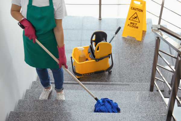 A woman is cleaning the stairs with a mop.
