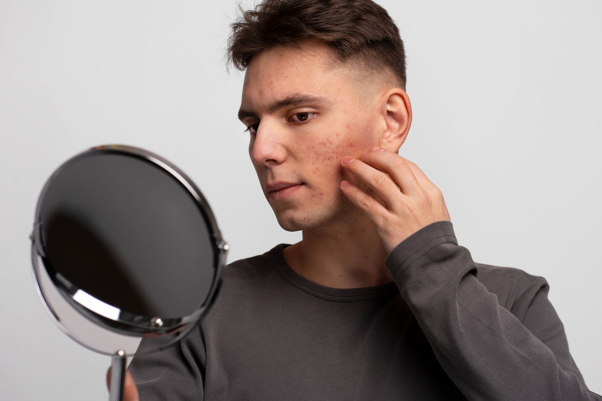 A man is looking at his face in a mirror.