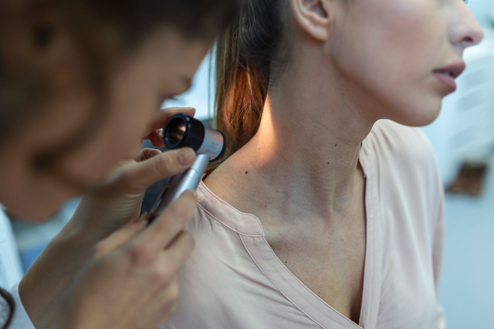 A doctor is examining a woman 's neck with a magnifying glass.
