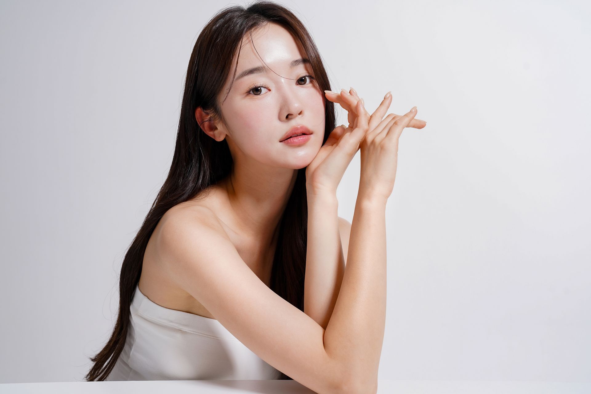 A woman is sitting at a table with her hands on her face.