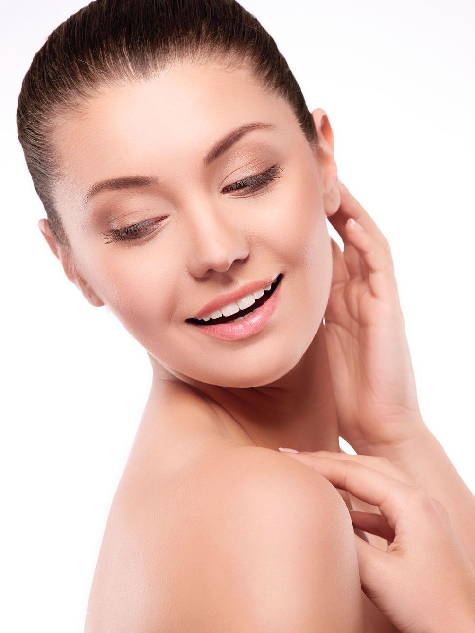 A woman is smiling and touching her face with her hand.