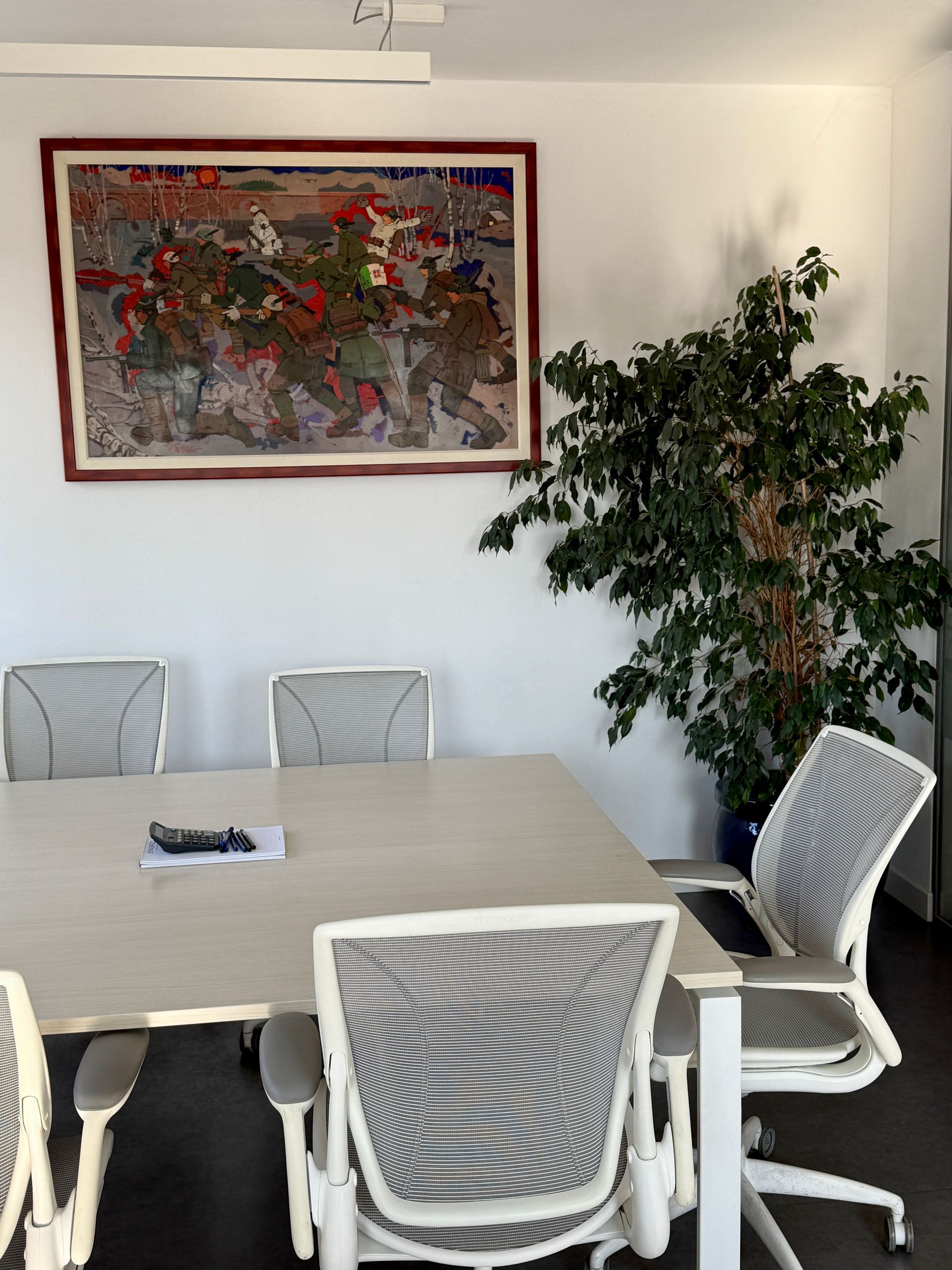 Una sala conferenze con un grande quadro sulla parete sopra il tavolo