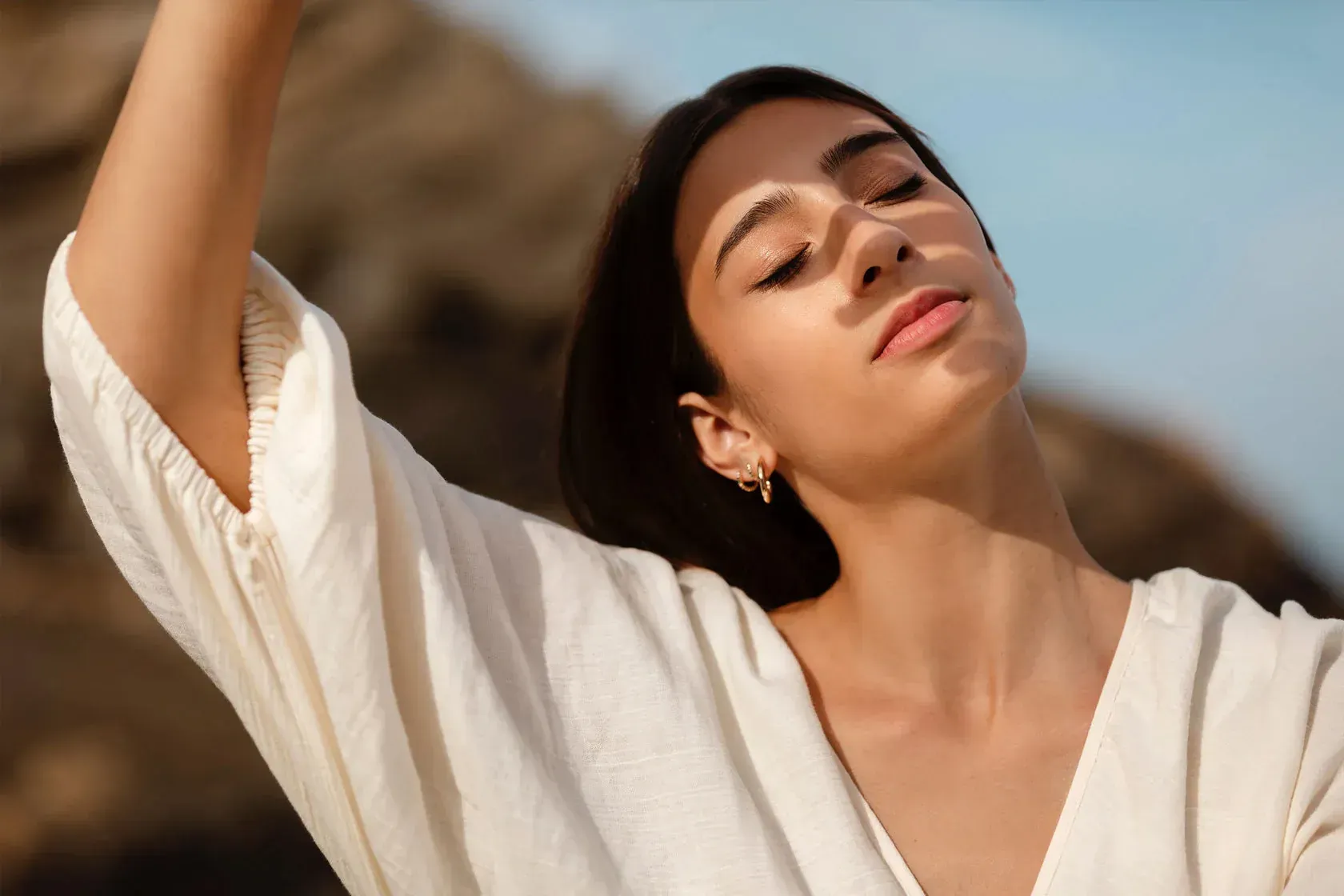 Woman With Eyes Closed, Reaching Up, Sunlight on Face — That Skin Clinic in Mooloolaba, QLD