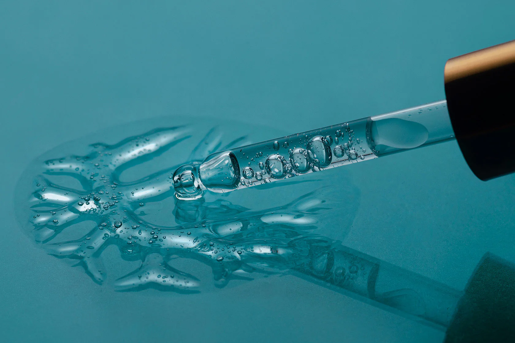 Dropper Dispensing Clear Serum Onto a Teal Surface — That Skin Clinic in Mooloolaba, QLD