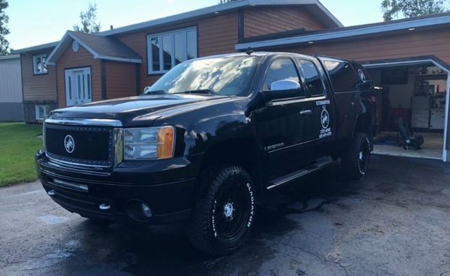 Un camion noir est garé devant une maison en briques.