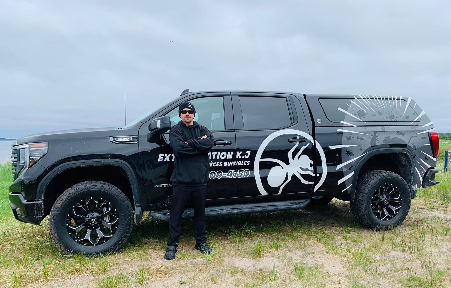 Un homme se tient à côté d'un camion noir avec une fourmi sur le côté.