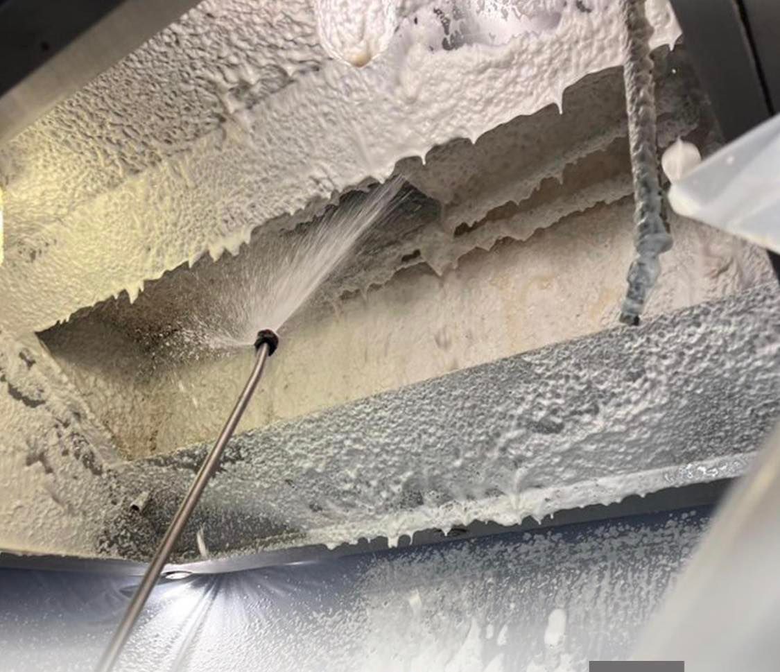 Une personne nettoie un plafond avec un nettoyeur haute pression.