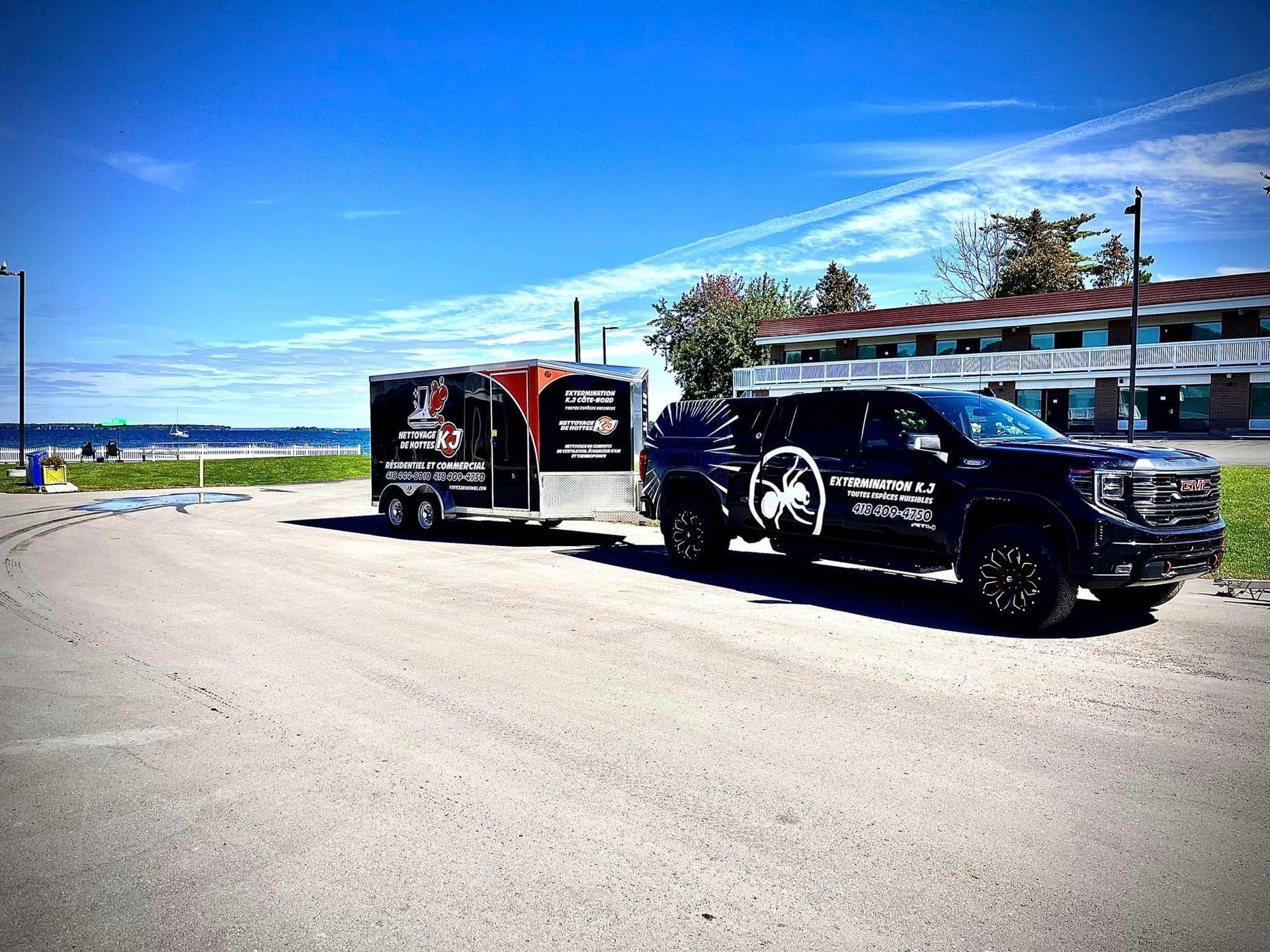 Un camion noir tracte une remorque sur un parking.