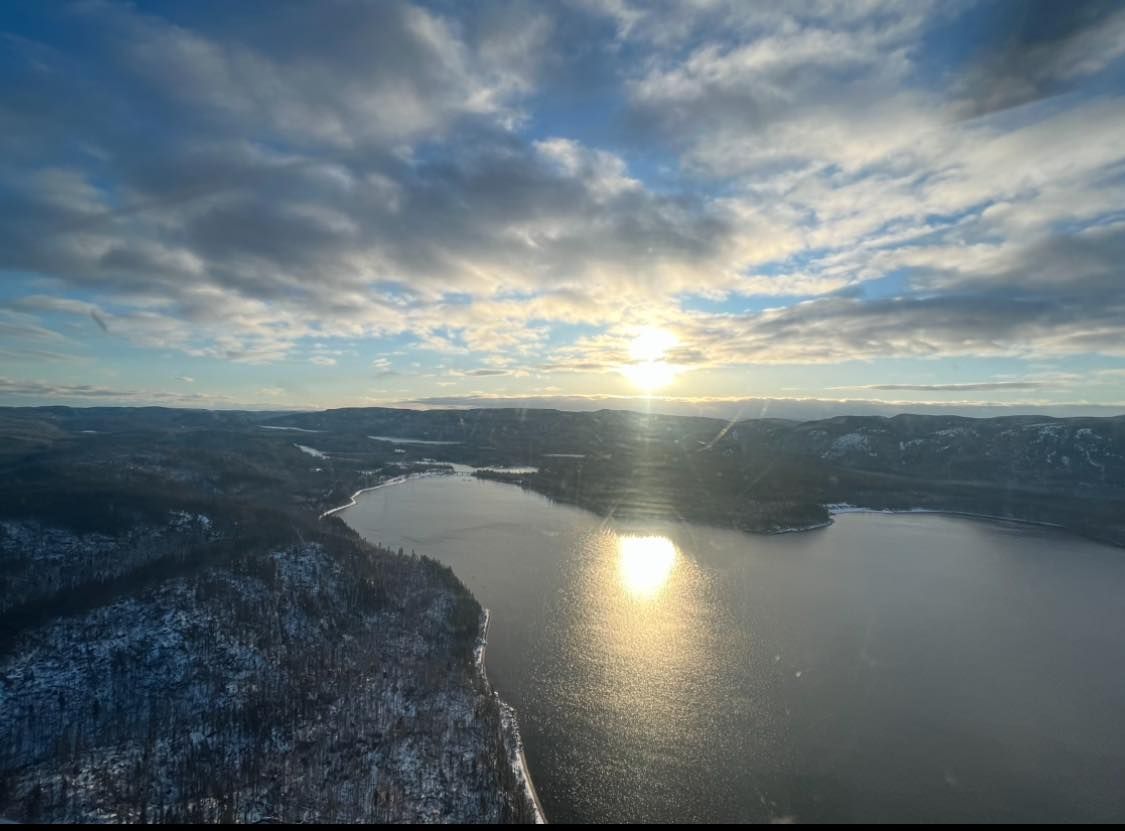 Une vue aérienne d'un lac avec le soleil qui brille à travers les nuages.