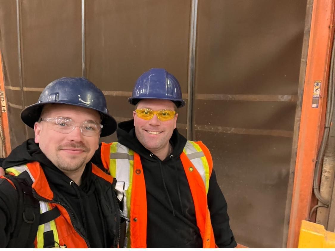 Deux hommes portant des casques et des gilets de sécurité posent pour une photo.