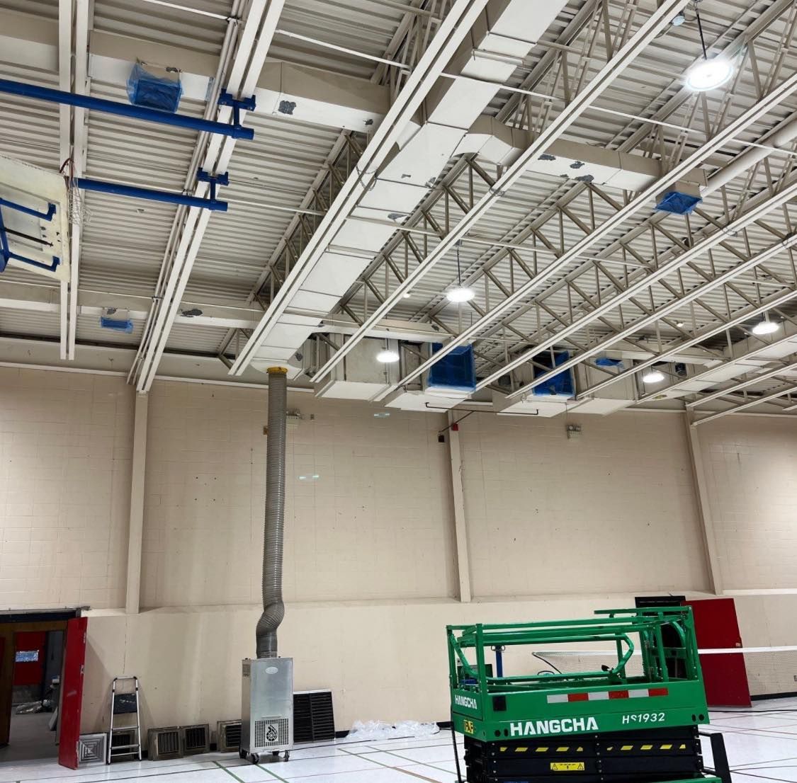 Une machine verte est garée dans une grande pièce avec un plafond très haut.