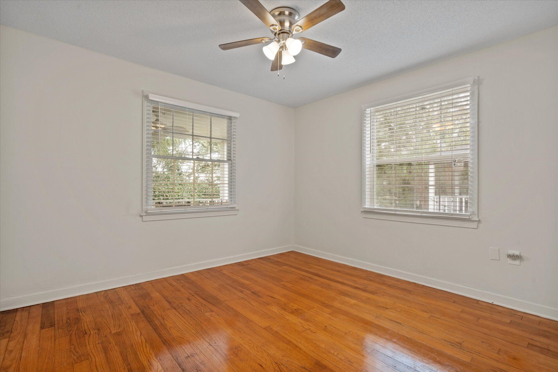 An empty bedroom with hardwood floors and a ceiling fan.