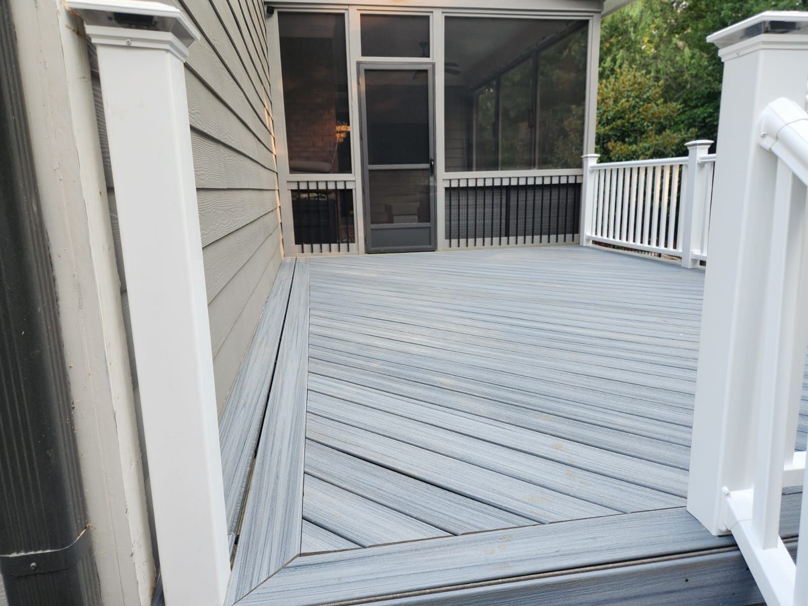 Wooden decks on a two-story house. Ground level shows retaining wall, stairs and leaves.