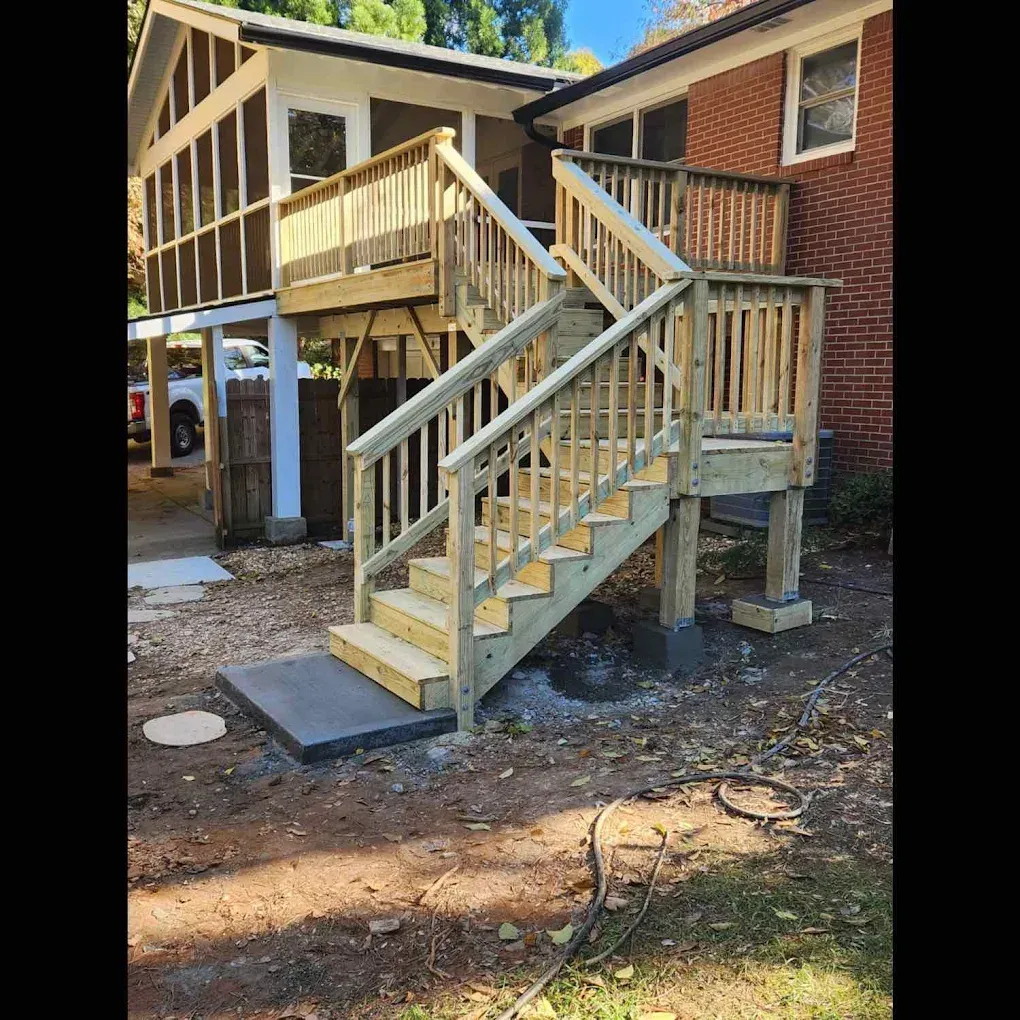 Wooden outdoor staircase leading to a deck on a brick house; construction.