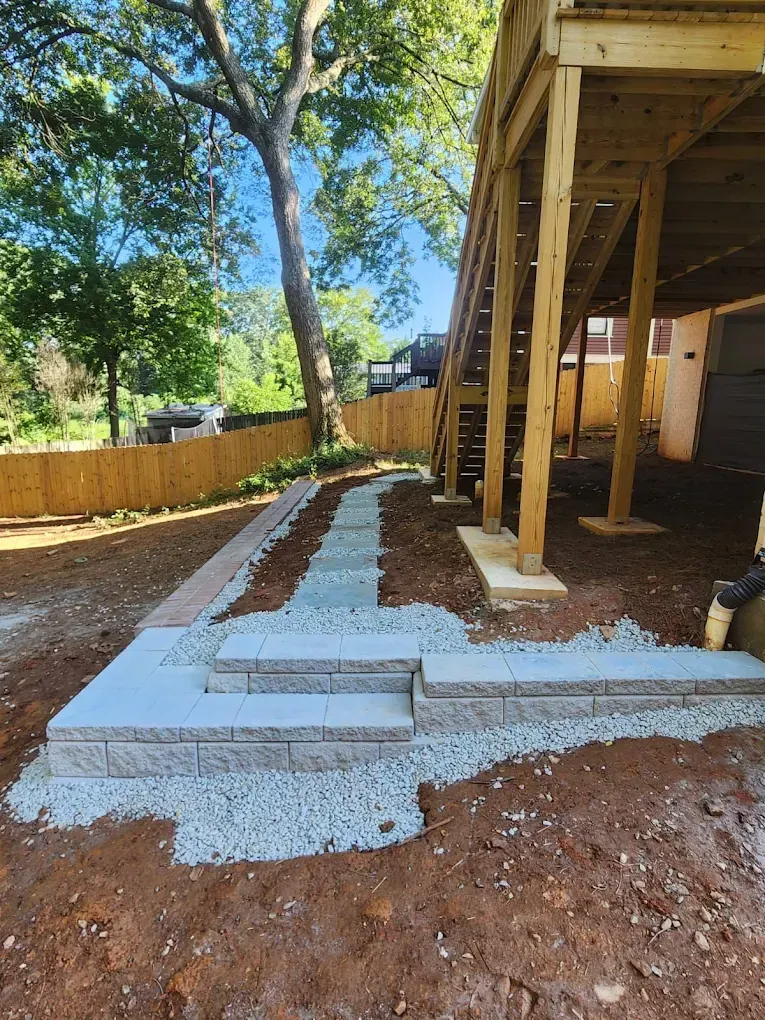 Backyard with stone steps, walkway, gravel, and wooden deck.
