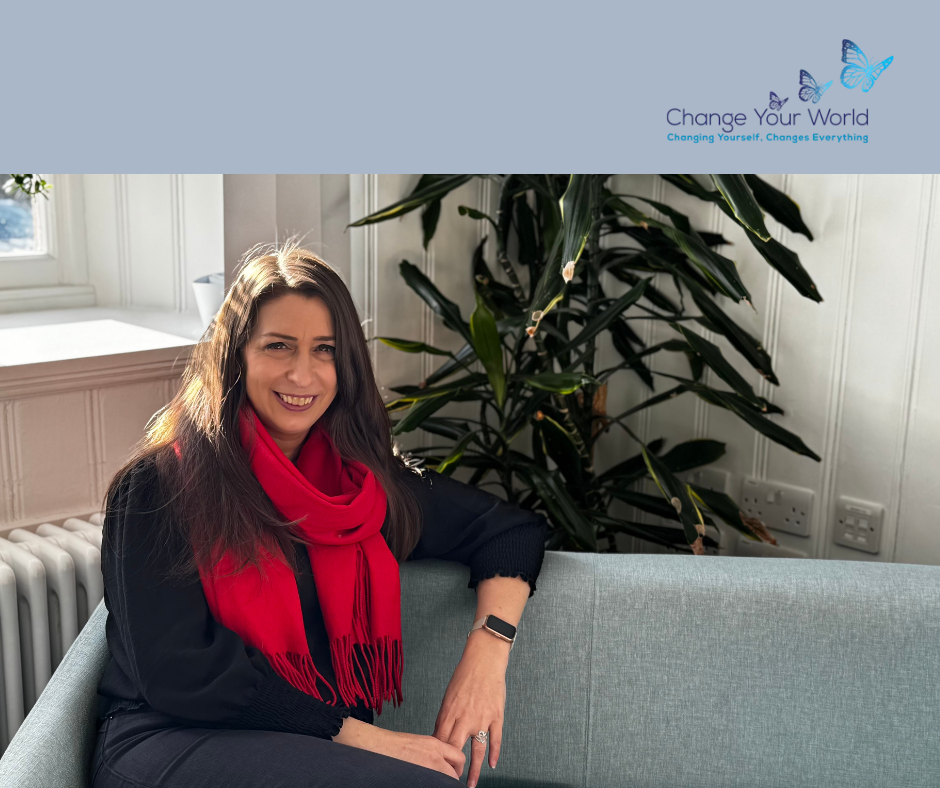 Woman in floral top smiles, standing in a brightly lit office setting.