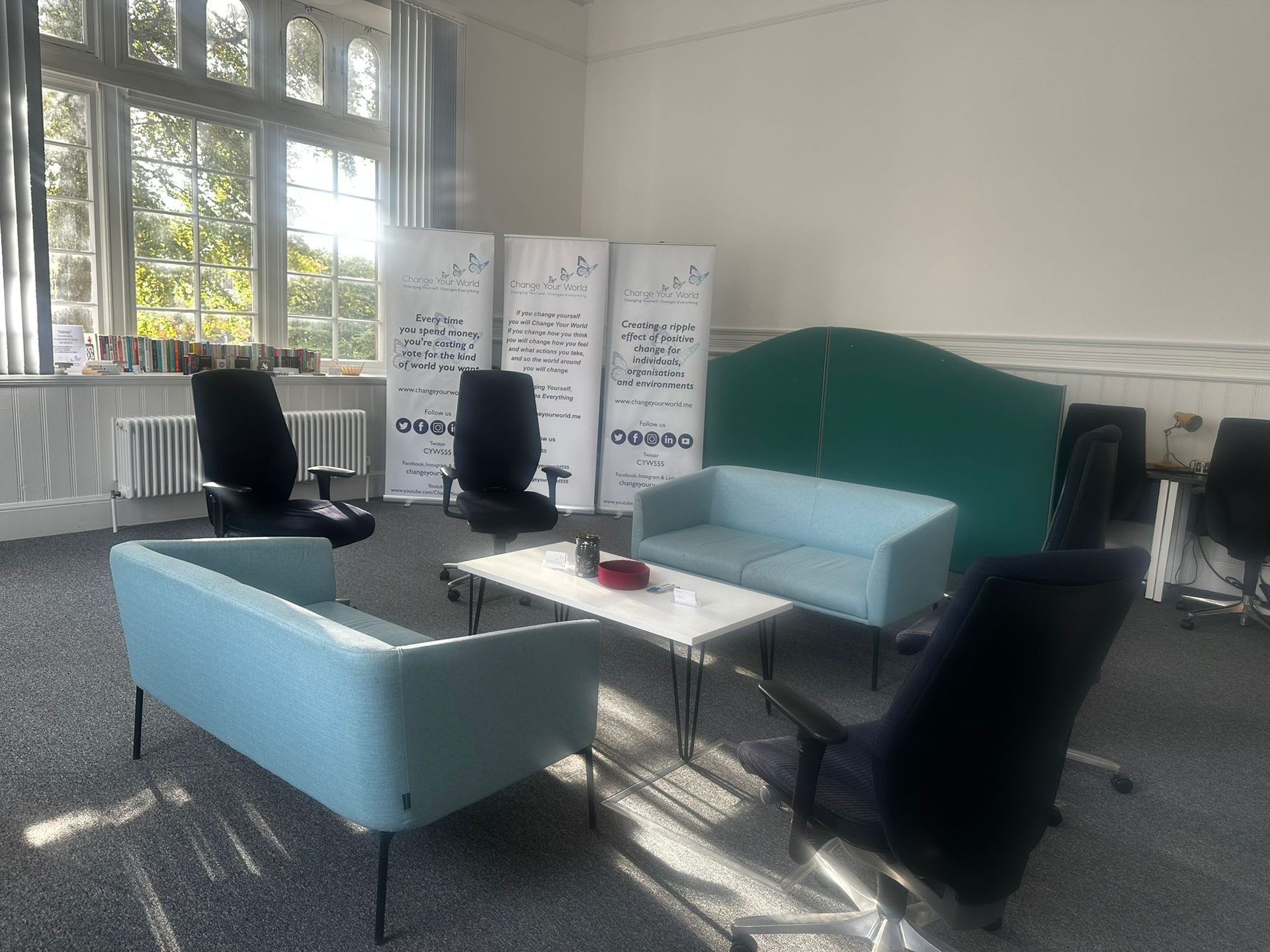 A bright room with a seating area. Two blue couches face each other around a small table.