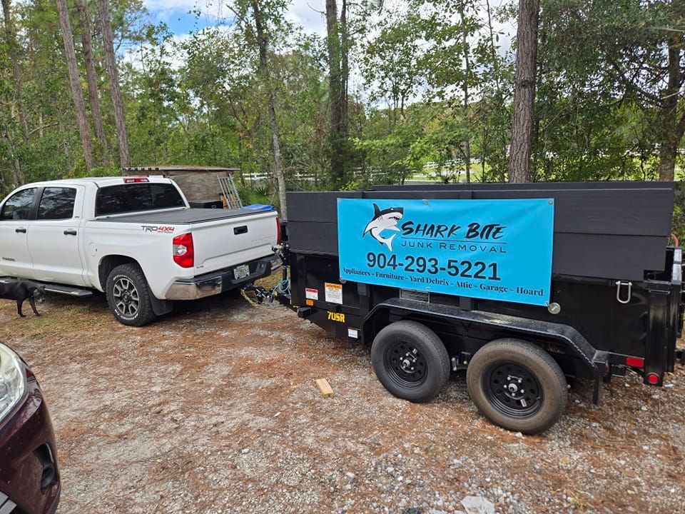 A white truck is towing a dumpster on a trailer.