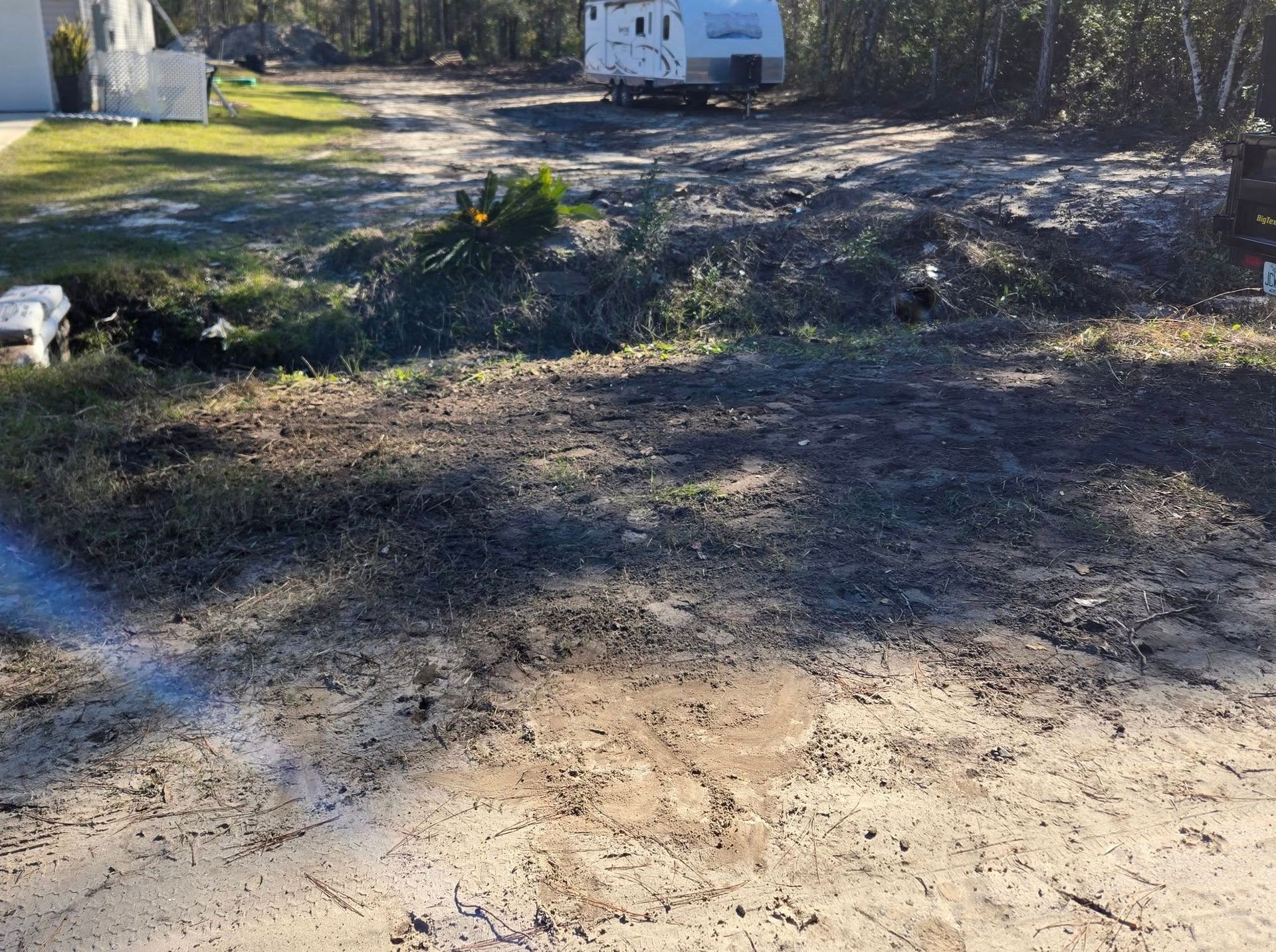 A white trailer is parked on the side of a dirt road.