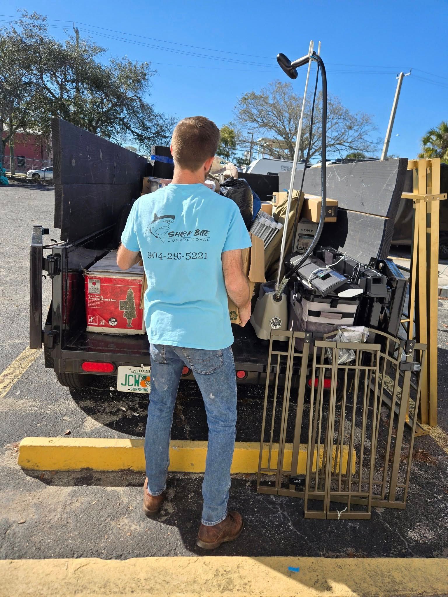 A man is standing in front of a dumpster full of junk.