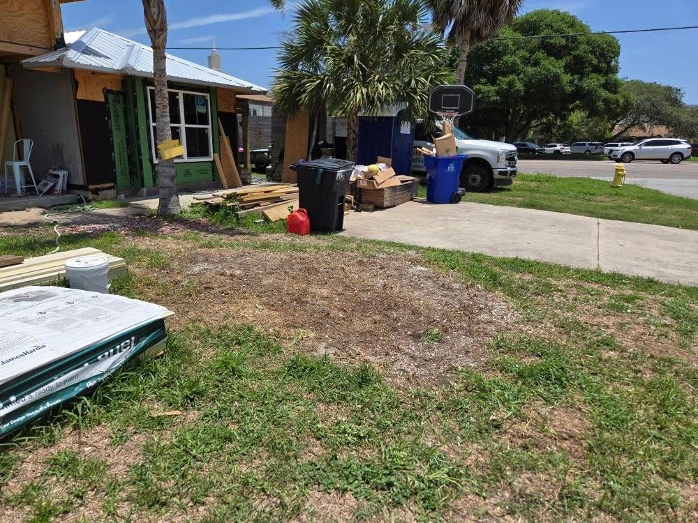 A house under construction with a lot of trash in front of it.